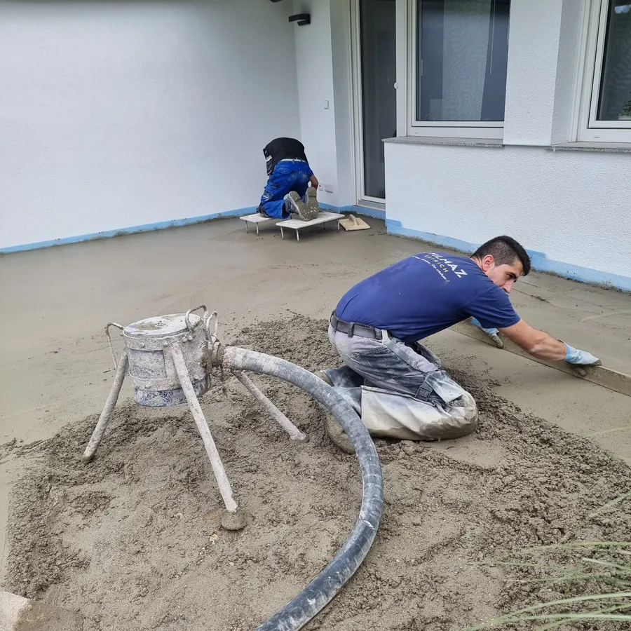 Mitarbeiter verlegen Verbundestrich auf einer Terrasse im Freien.