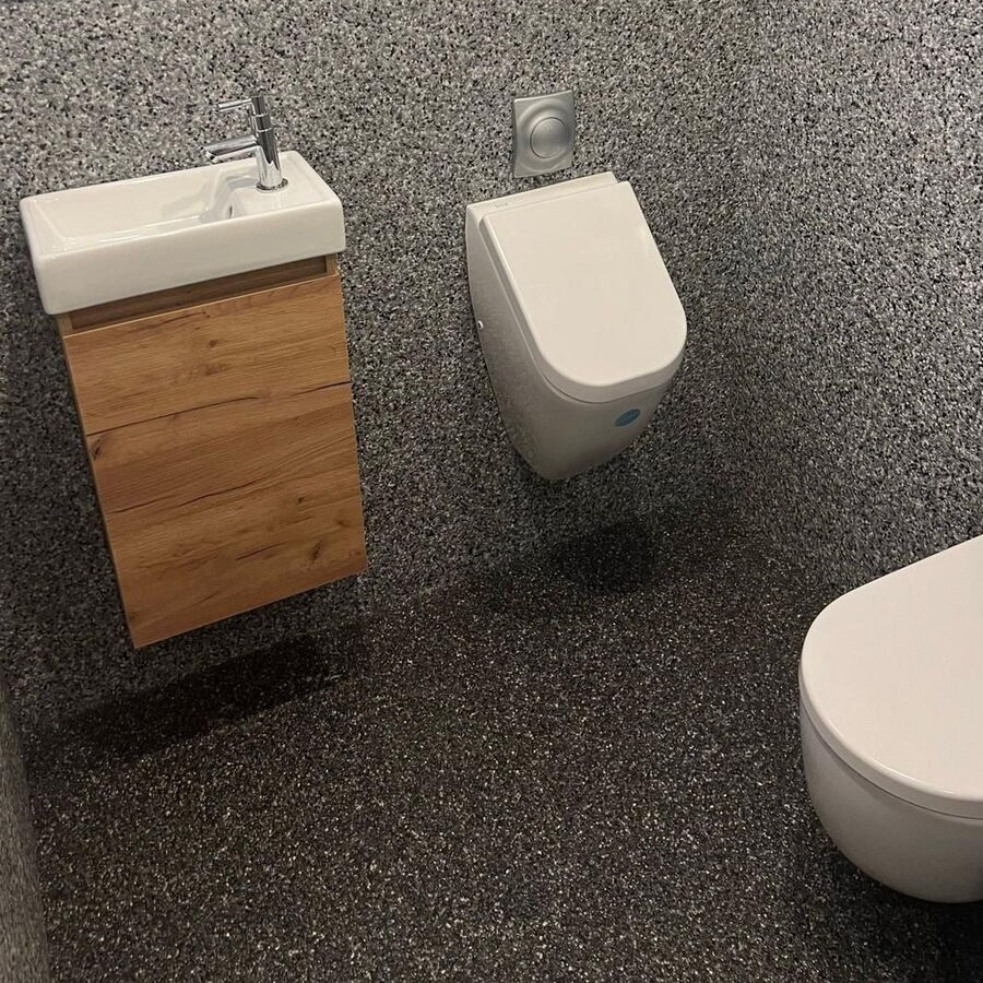 Gäste-WC mit dunklem Steinteppich an Wand und Boden