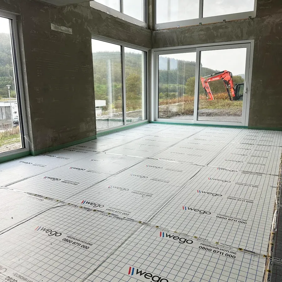 Perspektivansicht vom Innenraum eines Wohngebäudes im Rohbau. Auf dem Boden ist Trittschalldämmung verlegt.